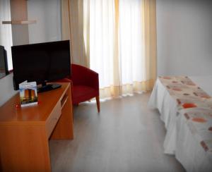 um quarto de hotel com uma televisão e uma cadeira vermelha em Hotel Alone em Cala de Finestrat