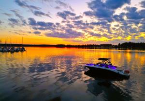 a small boat in the water at sunset at Riverside - nad rzeką, centrum, Netflix i Max, parking, winda in Iława +26 photos