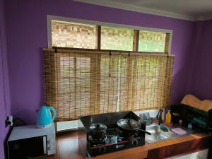 cocina con fogones y ventana con 2 sartenes en Cozy house near the sea, en Koh Samui  1 foto más