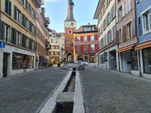 an empty street in a city with a clock tower at Maison de charme entre ville et campagne in La Neuveville