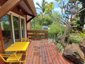 Una mesa y sillas amarillas en una terraza de madera. en Studio le Ti coin Charmant, en Saint-Joseph