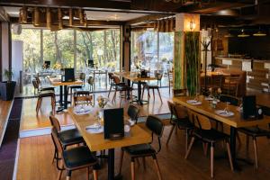 a restaurant with wooden tables and chairs and windows at Hotel Gradche in Kočani