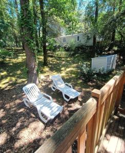 dos sillas blancas de jardín sentadas junto a un árbol en Mobil-home familial 3 chambres, en Saint-Brevin-les-Pins 28 fotos más