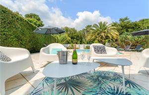 a patio with white chairs and a table with a bottle of wine at Beautiful Home In Lège-Cap-Ferret in Lège-Cap-Ferret