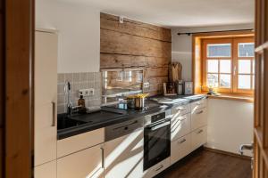 een keuken met witte kasten en een houten muur bij Ferienwohnung Landhaus Martin in Sonthofen