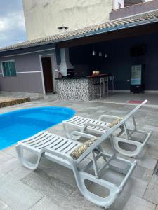 two white lounge chairs next to a swimming pool at Casa Encanto de Piri in Pirenópolis