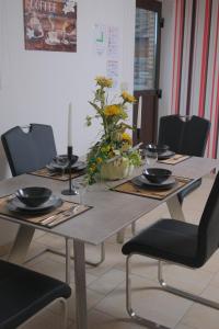 a dining room table with chairs and a table with flowers on it at Eifeltraum Marianus in Nieder-Emmels