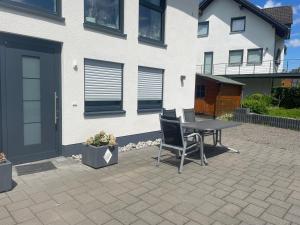 Un patio con una mesa y sillas frente a una casa. en Ferienwohnung Biggesee, en Drolshagen