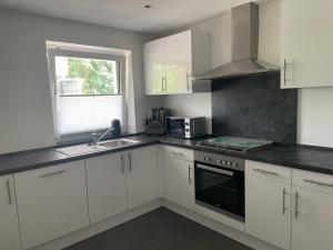 Una cocina con gabinetes blancos, un fregadero y un microondas. en Ferienwohnung Biggesee, en Drolshagen 2 fotos más