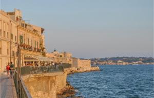 a group of people walking down a sidewalk next to the water at 6 Bedroom Pet Friendly Home In Siracusa in Siracusa +26 photos