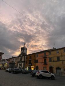 a building with a clock tower and cars parked in a parking lot at Romea in Campagnano di Roma