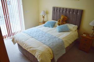 un ours en peluche assis sur un lit dans l'établissement Ruby's Watch, à Barmouth