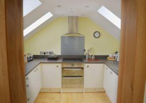 une cuisine avec des armoires blanches et une horloge au mur dans l'établissement Ruby's Watch, à Barmouth 8 autres photos