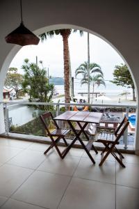 a table and chairs on a balcony with a view of the ocean at Pousada Quintal do Mar in Ubatuba