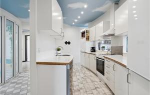 a kitchen with white cabinets and a tile floor at Beautiful Home In Ringkøbing With Sauna in Klegod