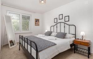 a white bedroom with a large bed and a table at Beautiful Home In Banjol With Sauna in Banjol