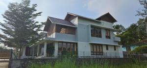 a white house with a tree in front of it at Grace villa in Piravam +44 photos