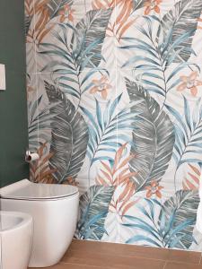 a bathroom with a toilet and a tropical wallpaper at Vidò Rooms in San Giuseppe Vesuviano