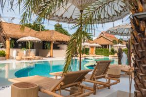 a swimming pool with lounge chairs and umbrellas at The Deck Cottages Samui in Bophut