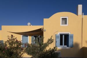 a yellow house with blue shutters on it at Villa Bonita Private Traditional house in Kamari