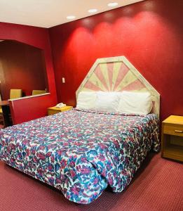 Cama en habitación de hotel con pared roja en Western Inn Express, en Hazlehurst