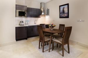 a kitchen with a wooden table and chairs in a room at Aswar Qurtubah Serviced Apartments Riyadh in Riyadh