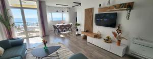 a living room with a television and a table with chairs at Green Apartment in Durrës