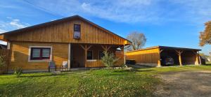 a wooden house with a porch and a shed at Haus an der Pferdekoppel am Blankenburger See in Blankenburg Oberuckersee