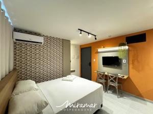 a bedroom with a bed and a desk and a tv at Flat No Bessa com Varanda Gourmet in João Pessoa