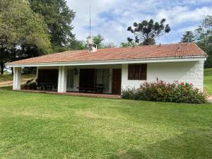 a small white house with a grass yard at El encuentro in Unquillo