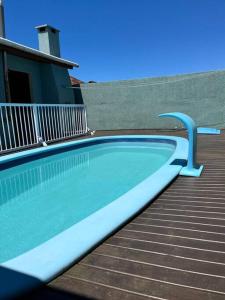 a swimming pool with a blue rail next to a building at Casa com piscina próximo ao centrinho - Nova Tramandaí in Tramandaí