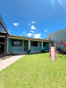 a house with a lawn in front of it at Casa com piscina próximo ao centrinho - Nova Tramandaí in Tramandaí