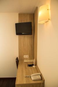 a desk with a phone and a television on a wall at Logis Des Trois Massifs in Claix