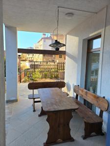 a patio with a wooden table and benches on a balcony at Вила 5 - Планински перли in Stoykite
