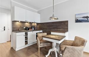 a kitchen with white cabinets and a table and chairs at Baltischer Hof Apartment 19 in Boltenhagen