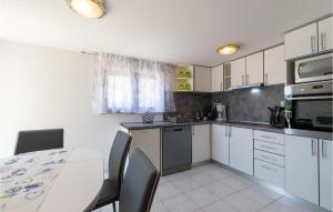 a kitchen with white cabinets and a table with chairs at Holiday Home Rtina 24 in Rtina +29 photos