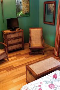 a room with a tv and a chair and a dresser at Hotel Rural La Cabaña in Palazuelos