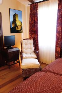 a bedroom with a bed and a chair and a tv at Hotel Rural La Cabaña in Palazuelos