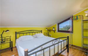 a bedroom with a bed with yellow walls and a window at Nice Home In Njivice With Wifi in Njivice