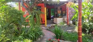 a garden in front of a red house at Hotel y Restaurante Playa Linda in San Pedro La Laguna
