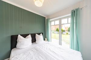 a bedroom with a bed with white pillows and a window at Traumhaus mit Garten in Reppenstedt
