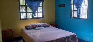 a bedroom with a bed with blue walls and windows at Hotel y Restaurante Playa Linda in San Pedro La Laguna