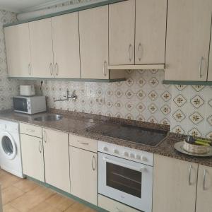 a kitchen with white cabinets and a stove top oven at Los Tilos in Ramales de la Victoria