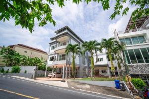 patong villa3 四卧海景泳池别墅 近班赞海鲜市场 中英泰三语服务 في شاطيء باتونغ: عمارة بيضاء فيها نخل قدام شارع