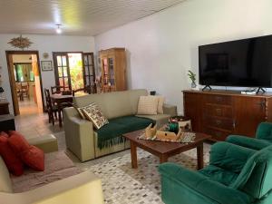 a living room with a couch and a tv at Estadia Rose - Quarto 2 in São Gabriel