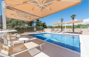 a swimming pool with umbrellas and chairs and a swimming poolvisor at Amazing Apartment In Novalja With Wifi in Novalja