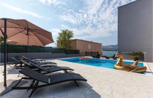 a swimming pool with lounge chairs and an umbrella at Nine-Bedroom Holiday Home In Arbanija in Trogir