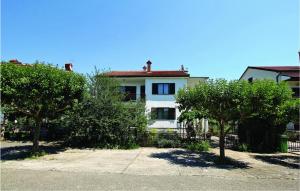 Biały dom z drzewami przed nim w obiekcie Awesome Apartment In Umag With Wifi w mieście Umag