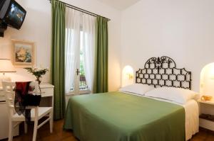a bedroom with a green bed and a desk and a window at Hotel Villa Angelica in Ischia