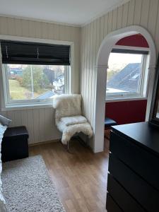 a living room with a chair and two windows at Nydelige Tromsdalen - rom i enebolig in Tromsø +8 photos